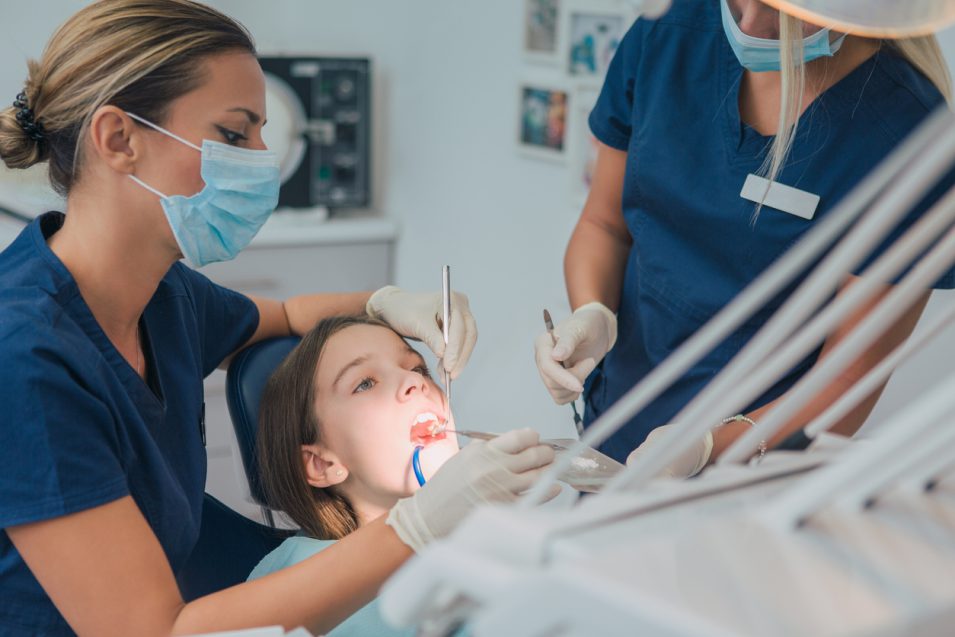 Pediatric dentistry. Dentist examining a young girl