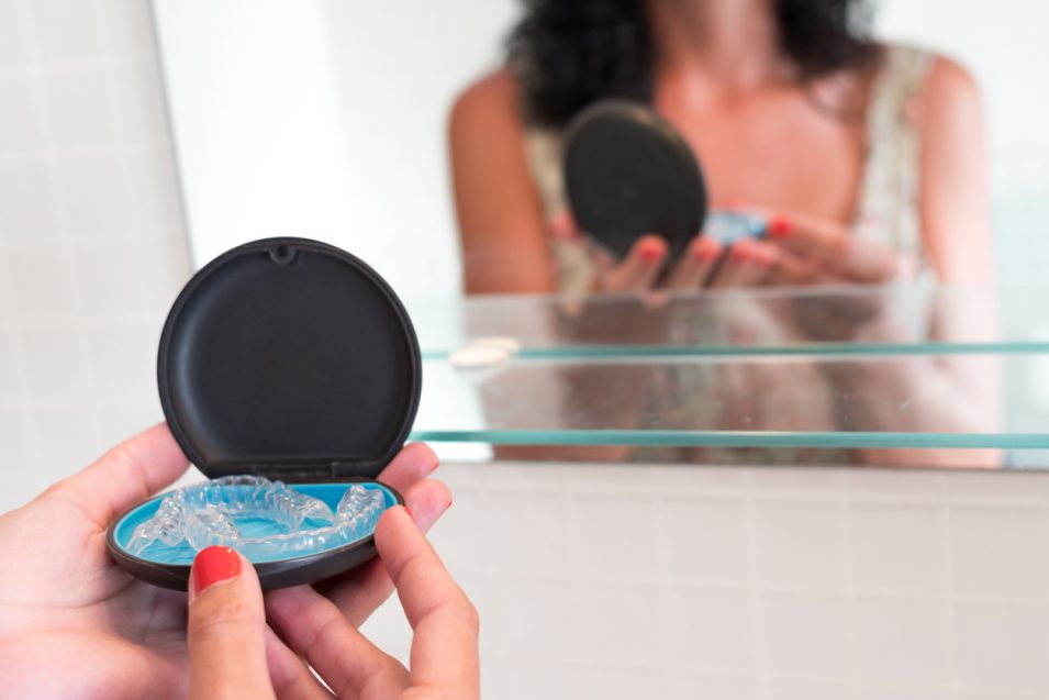 Young woman's hands holding the case where she keeps her invisible silicone aligners for dental correction. mobile orthodontics