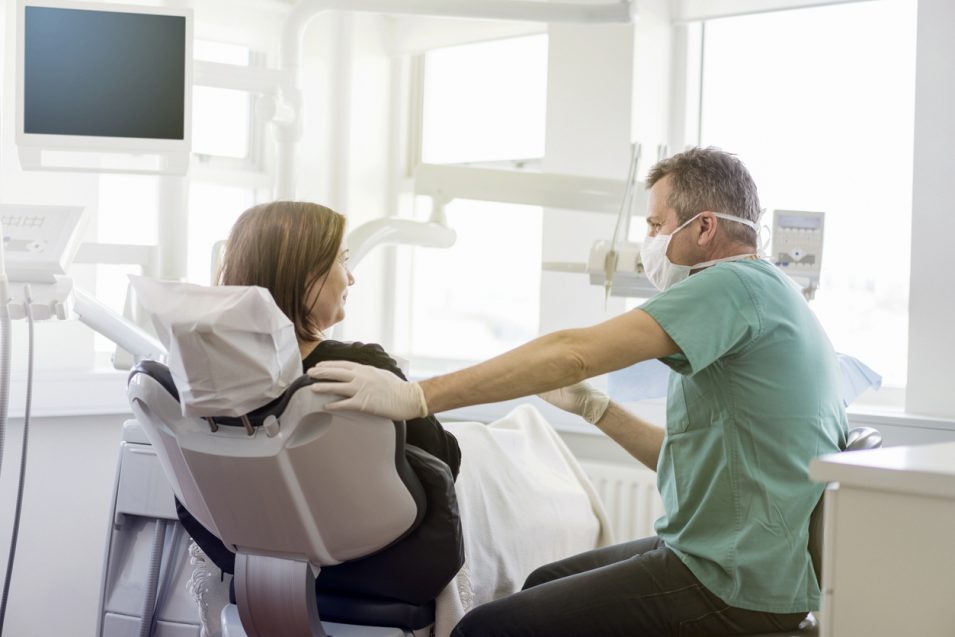 Dentist talking to female patient in clinic