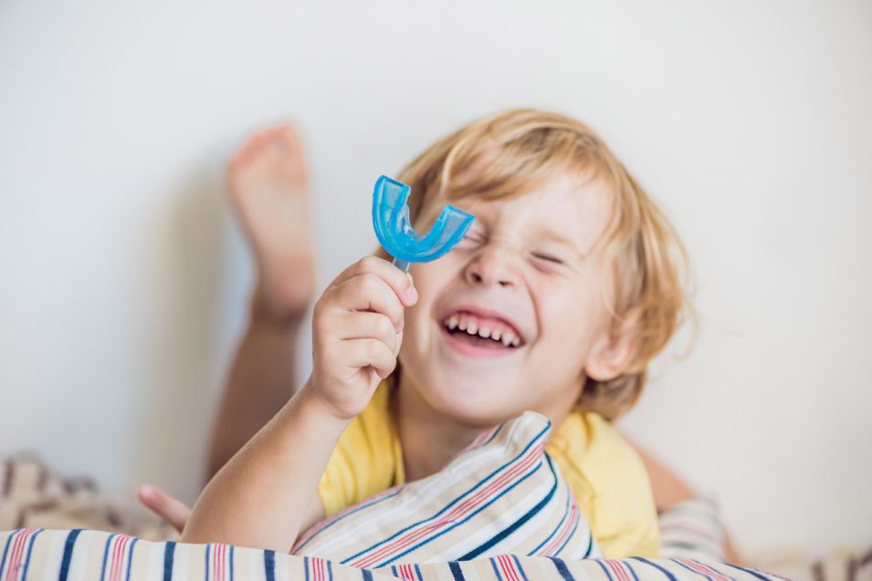 Three-year old boy shows myofunctional trainer. Helps equalize the growing teeth and correct bite, develop mouth breathing habit. Corrects the position of the tongue