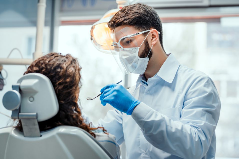 dentist performing oral cancer screening at hamilton clinic