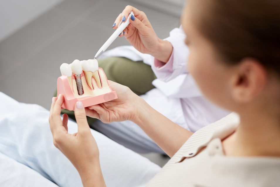 girl holding a dental implant model at hamilton clinic