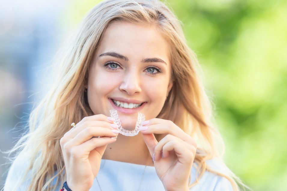 young girl outside holding clear braces in hamilton